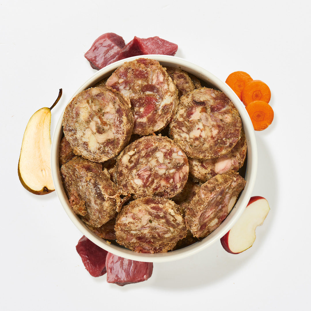 BARF Komfort PLUS Pferdefleischtaler mit Karotten, Äpfeln und Birnen in weißer Schale, rohes Pferdefleisch und Obststücke daneben
